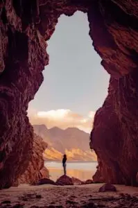 man sieht ein Felsentor, in der Mitte steht ein Mensch auf einem Stein, und symbolisiert Freiheit und Aufbruch